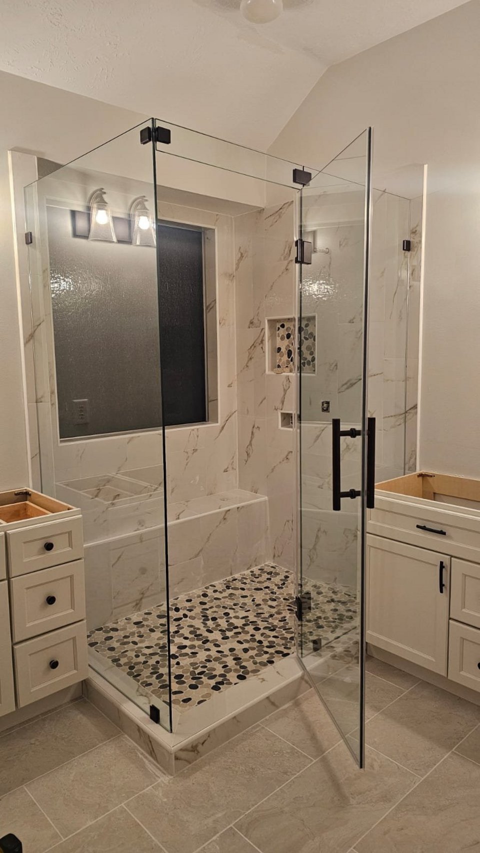 Ejemplo de ángulo 90° sobre muros / muretes de Glas Plus: vidrio clear con herraje negro en esquina de 90°, con banca dentro del shower