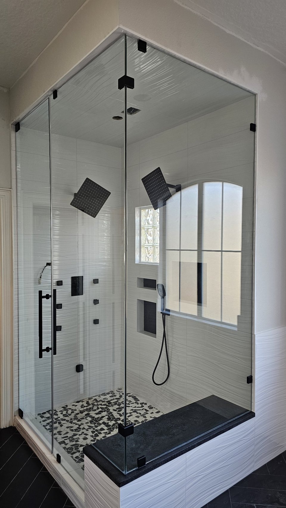 Ejemplo de ángulo 90° sobre muros / muretes de Glas Plus: vidrio clear con herraje negro, con un panel montado sobre un murete a modo de banca
