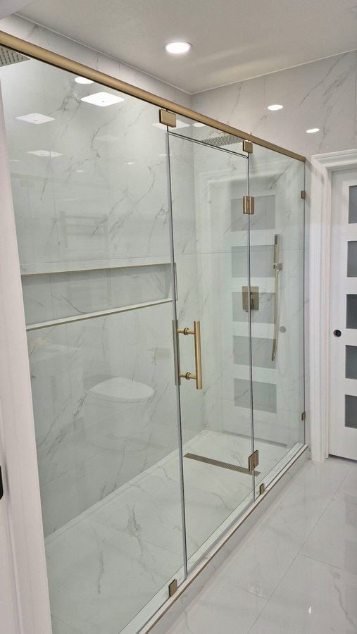 Ejemplo de puerta de bisagras con paneles laterales CON barra superior de Glas Plus: una barra brush gold une los paneles por arriba