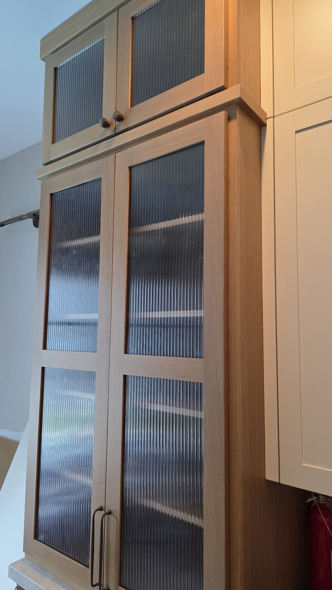 Ejemplo de vidrios de gabinetes de Glas Plus: gabinete alto de madera con puertas de vidrio estriado