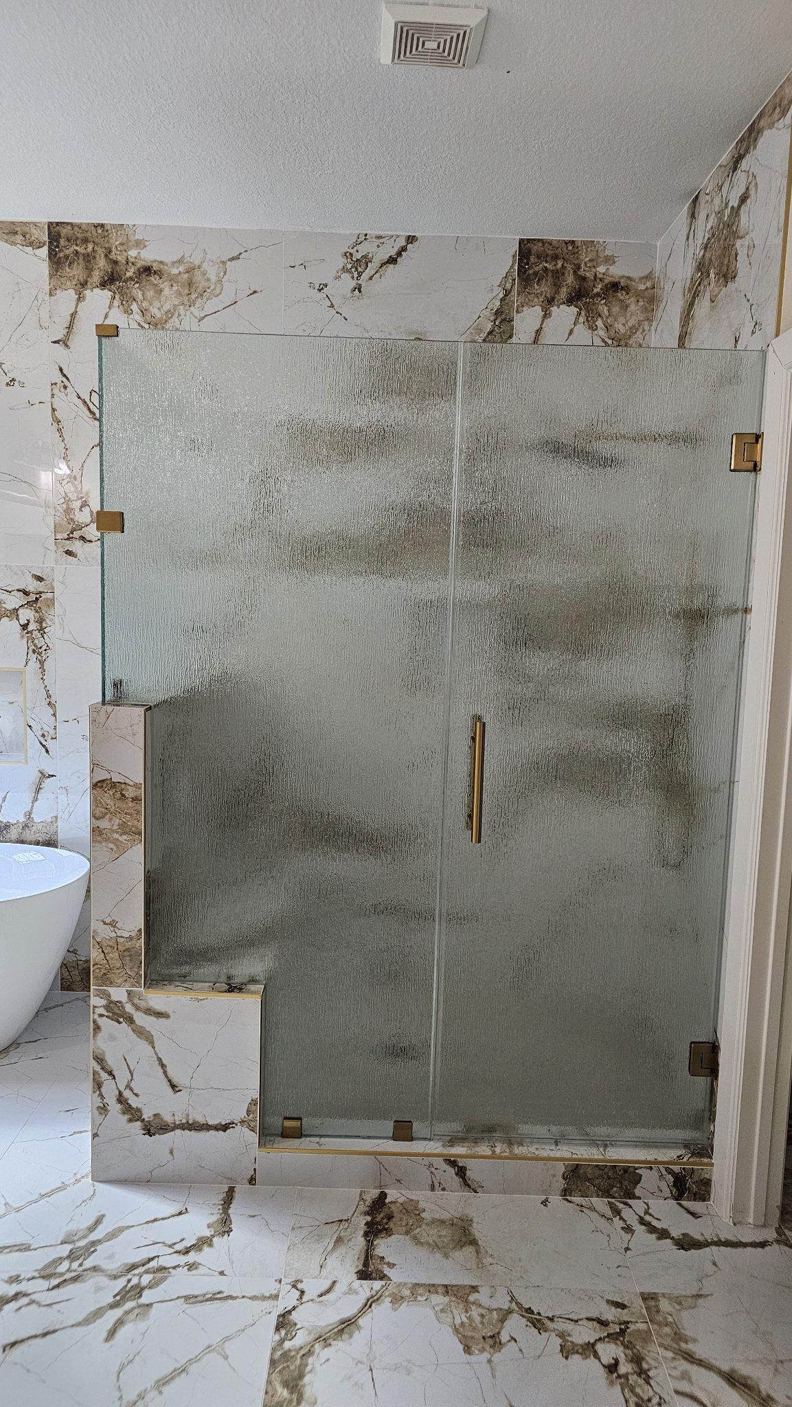 Trabajo de Glas Plus: shower en línea recta con vidrio Rain (textura de lluvia), notch sobre una banca de mármol y herraje dorado
