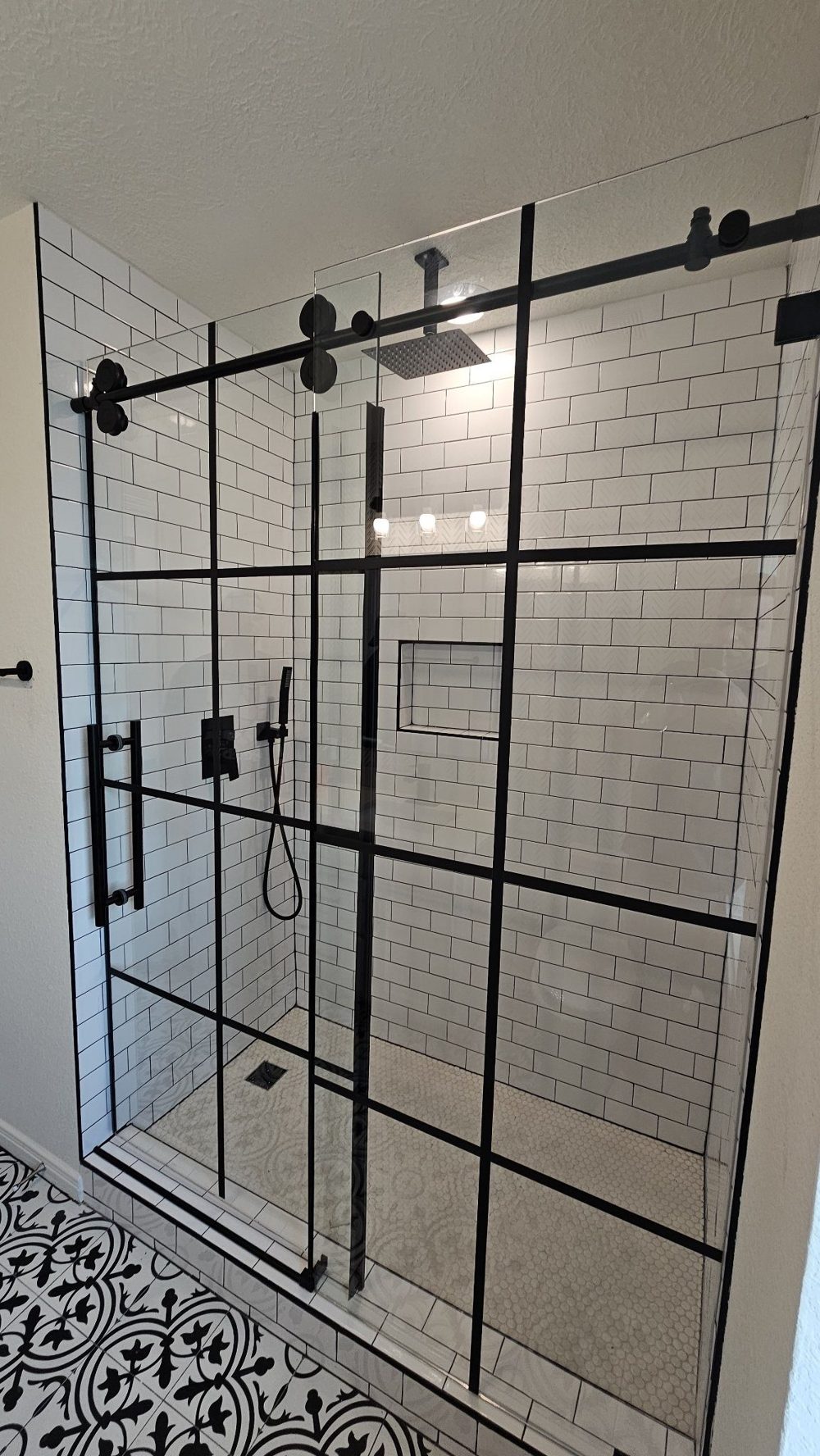 Trabajo de Glas Plus: sliding de una puerta con panel fijo, estilo industrial con marco y rejilla negra, en shower de azulejo subway blanco