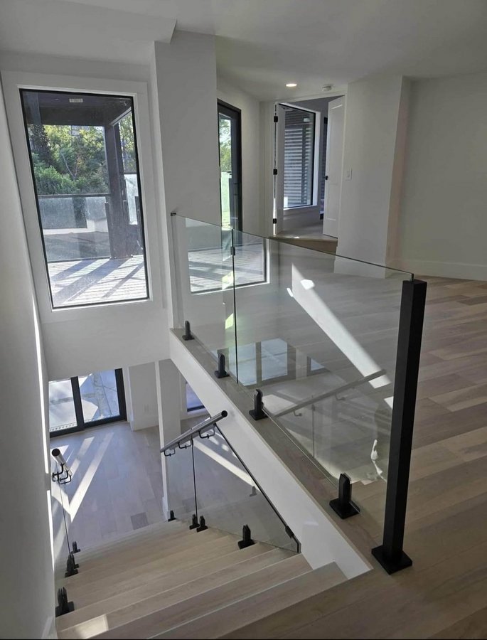 Ejemplo de escaleras de Glas Plus: barandal de vidrio en escalera y descanso superior, con postes y herraje negro
