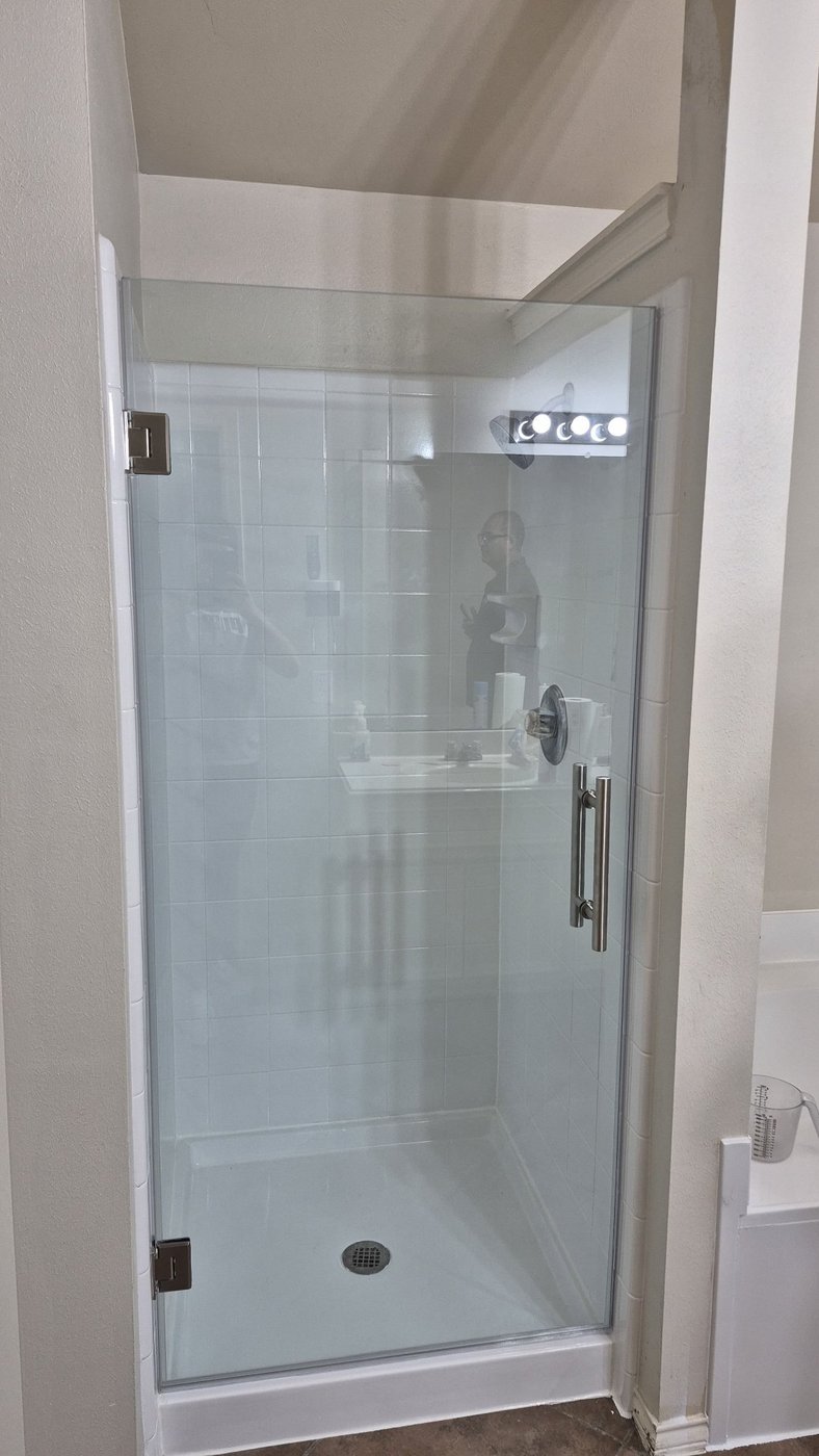 Single door con herraje brush nickel instalada por Glas Plus en un shower de azulejo blanco