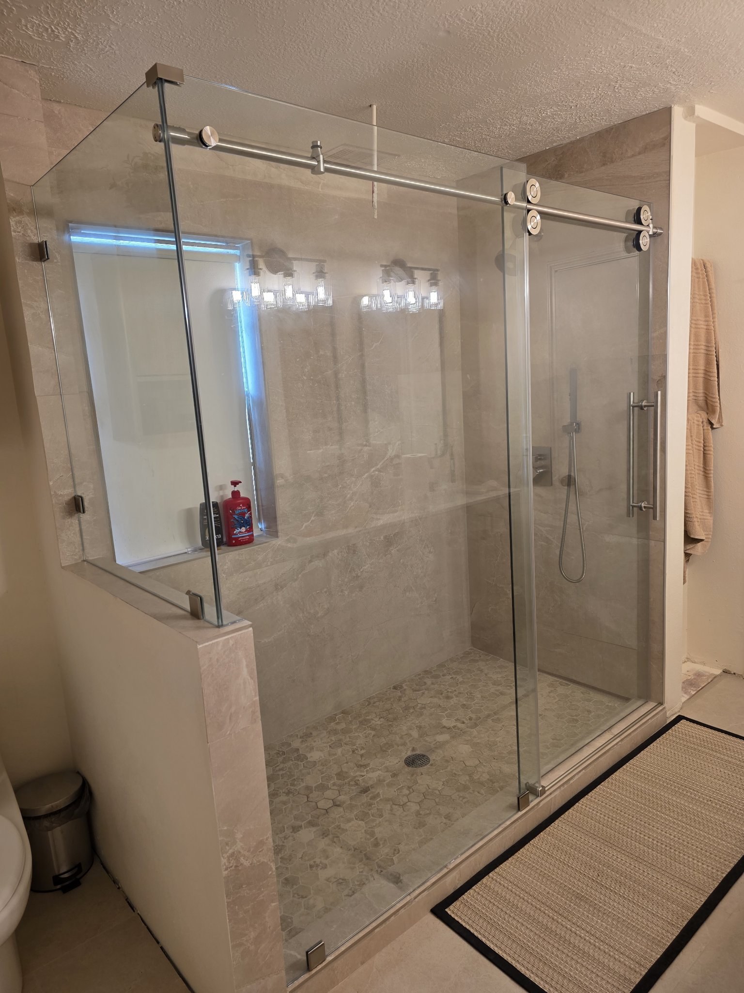 Sliding con retorno sobre medio muro con herraje cromado en shower de azulejo beige