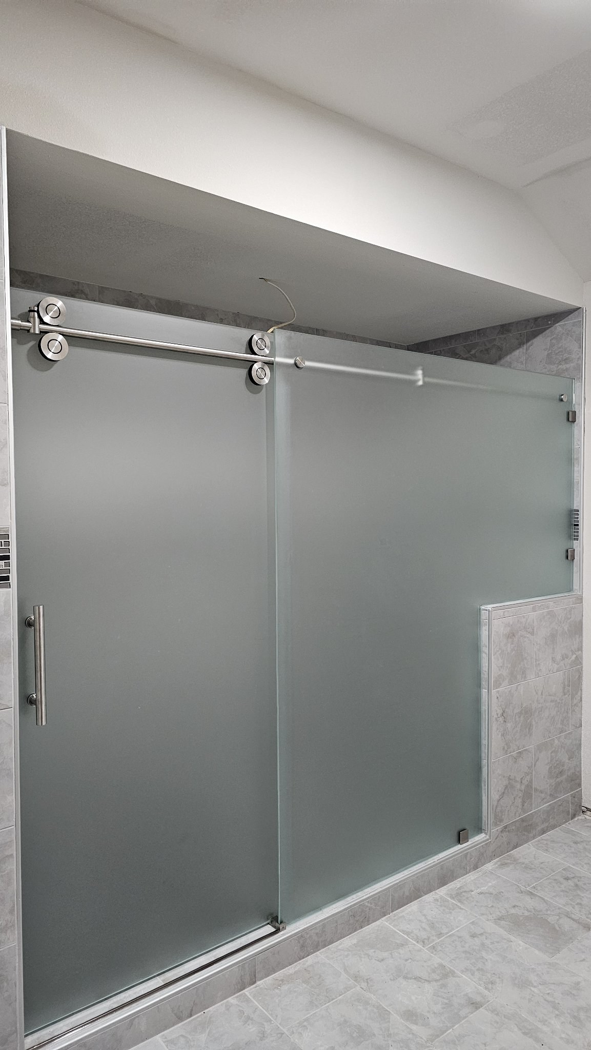 Sliding de una puerta con vidrio Frosted (opaco), riel de níquel cepillado y panel fijo con notch sobre medio muro