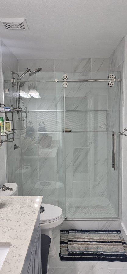 Sliding de una puerta con riel cromado y panel fijo en shower de azulejo oscuro