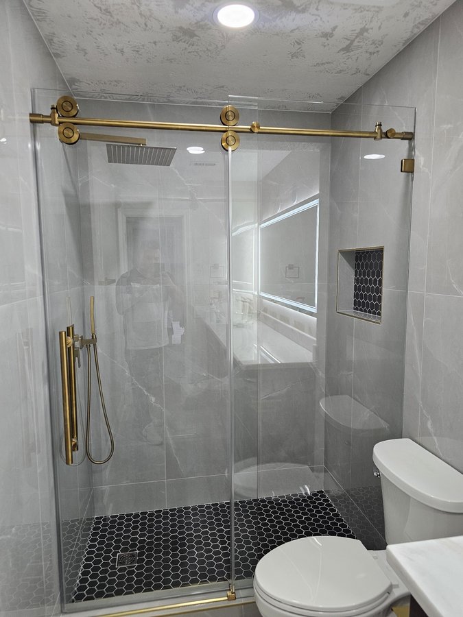 Sliding de una puerta con riel dorado y toallero en shower con nicho