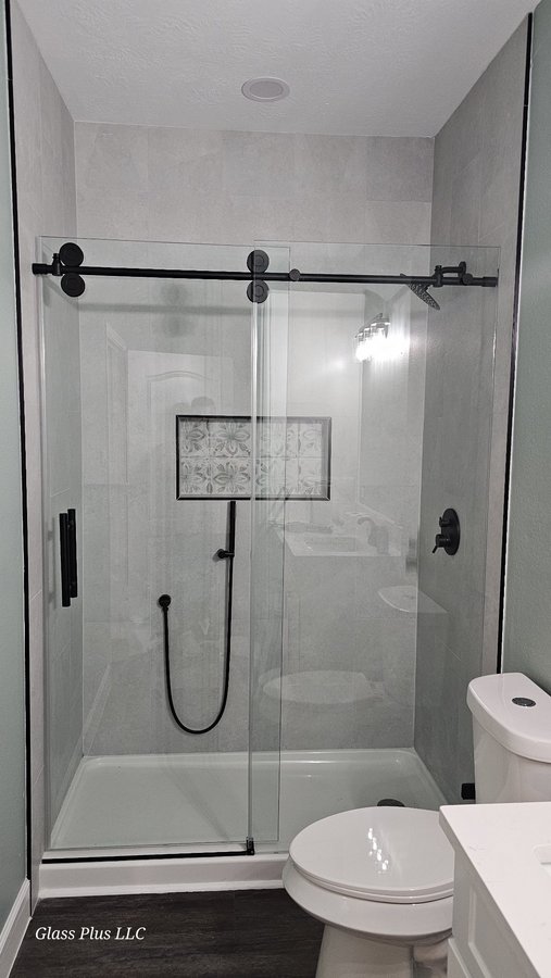 Sliding de una puerta con riel negro y panel fijo en shower de azulejo gris