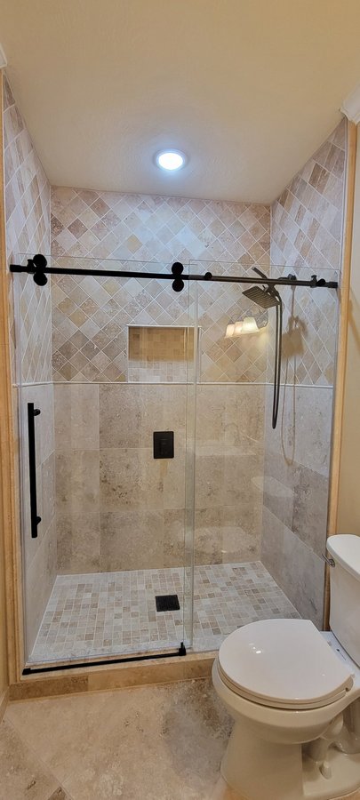 Sliding de una puerta con riel negro y panel fijo en shower de azulejo claro